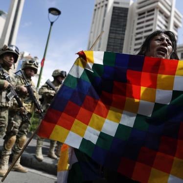 A demonstrator holds a Wiphala flag in front of soldiers blocking a street in downtown La Paz, Bolivia, Friday, Nov. 15, 2019.