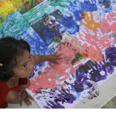 A girl covers anti-LGBT messages in rainbow handprints during a Pride rally in Manila on June 27, 2015. 