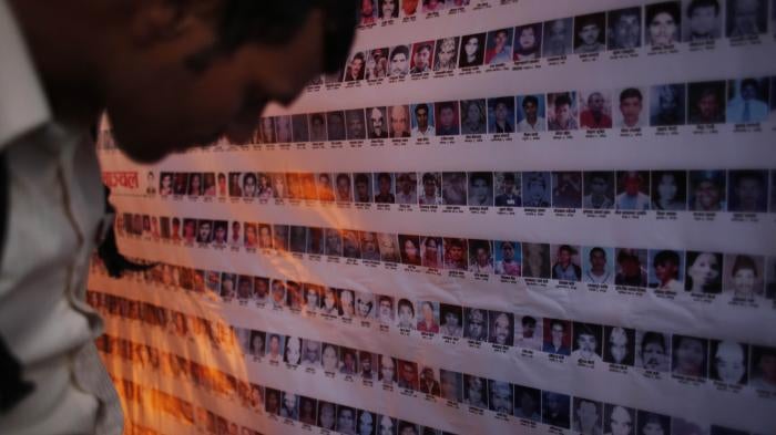 A man looks at a wall of portrait photos