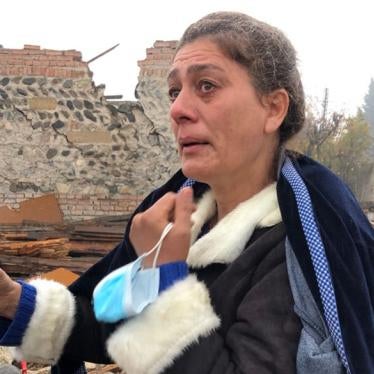 Shaira Guliyeva, 47, stands in front of her destroyed home and shows a photograph of her nephew, Arthur Guliyev, 13, who was killed there by a ballistic missile attack on October 17.