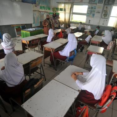 Schoolgirls sit at desks in a classroom