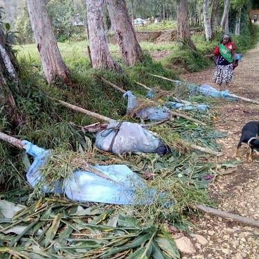 In this July 8, 2019 file photo, locals stand near the bodies of victims recovered following tribal violence in Karida, Papua New Guinea.