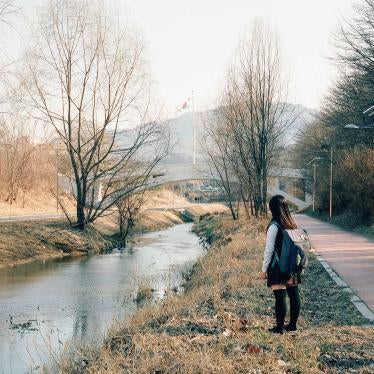 A schoolgirl stands next to a stream 