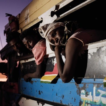 Men and women lean out of the windows of a bus