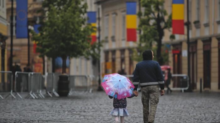 A little girl walks holding an umbrella in the Transylvanian town of Sibiu, Romania, Tuesday, May 7, 2019. (AP Photo/Vadim Ghirda)