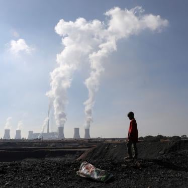 A child collects coal in front of a coal-fired power plant