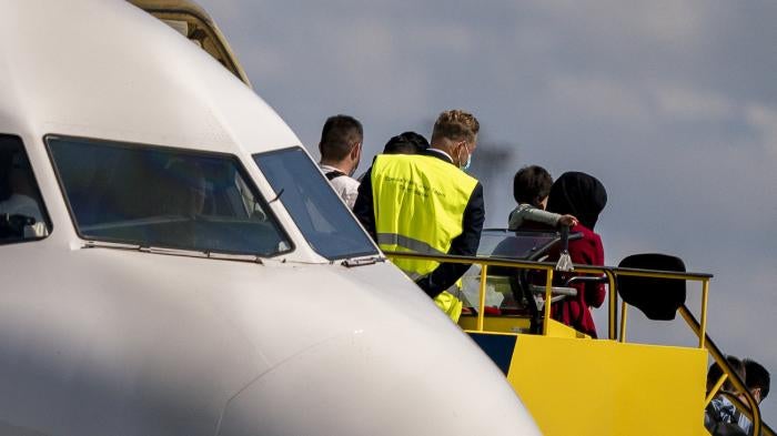 An Afghan woman carries a child as she disembarks at Copenhagen Airport.