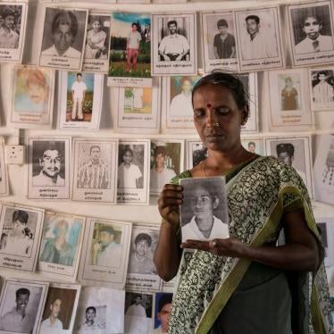 A woman holds a framed photo in front of a wall of other photos