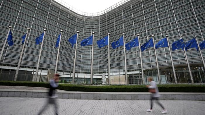 European Union flags wave in the wind as pedestrians walk by EU headquarters in Brussels, Wednesday, Sept. 20, 2023.