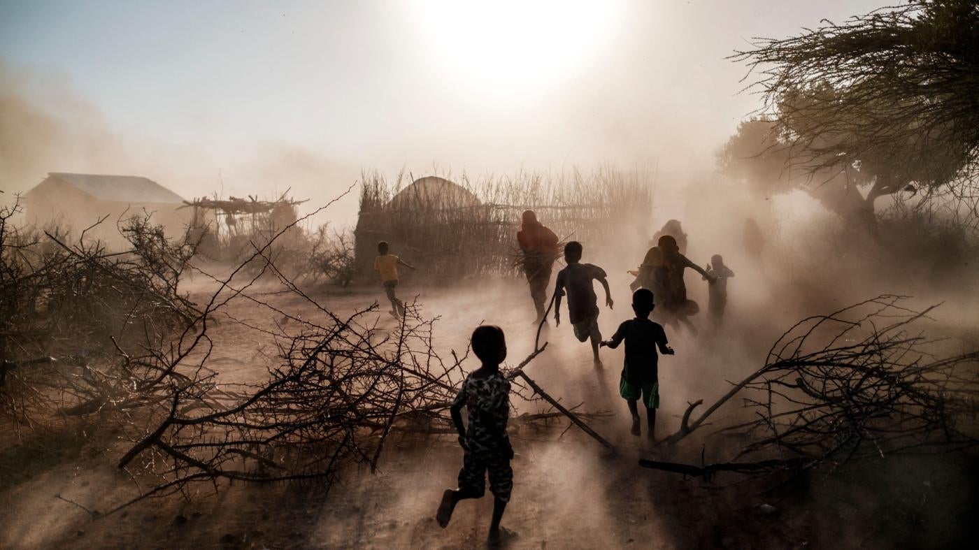 Children and women run among a cloud of dust at the village of El Gel, in Ethiopia’s Somali region, on January 12, 2023. The last five rainy seasons since the end of 2020 have failed, triggering the worst drought in four decades in Ethiopia, Somalia and Kenya.