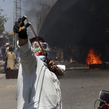 A protester aims a slingshot towards police (unseen)