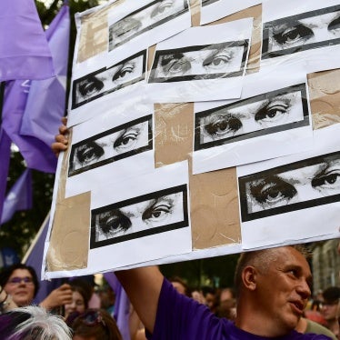 A man holds a banner showing the eyes of Hungarian Prime Minister Viktor Orban during a protest