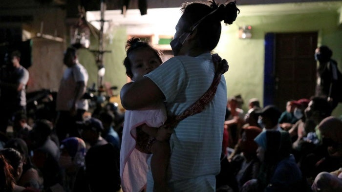 An undocumented migrant holds her daughter while being detained during an immigration raid