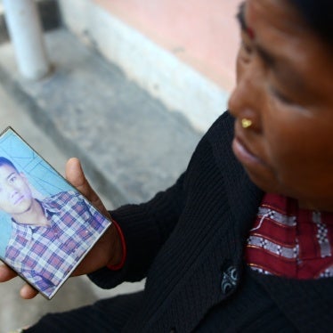 A woman displays a photograph of her son