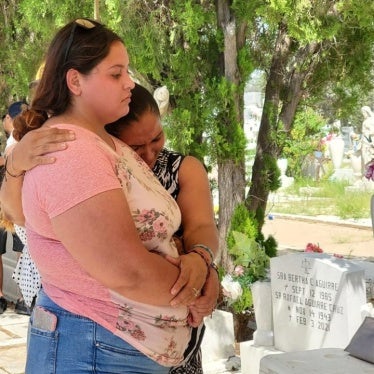 Two women embrace at a cemetery