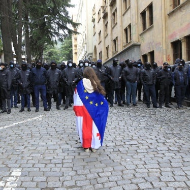 A demonstrator draped with the Georgian national and EU flags stands in front of police who are blocking the way to the parliament building, during a protest against the “foreign agent” law in Tbilisi, Georgia, May 14, 2024.