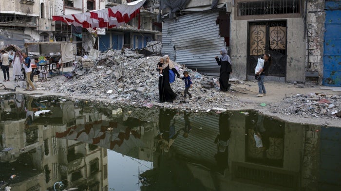 Palestinians displaced by the Israeli air and ground offensive walk next to sewage flowing into the streets of the southern town of Khan Younis in Gaza, July 4, 2024.