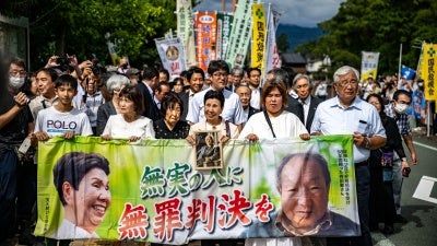 Iwao Hakamata, a former professional boxer who was sentenced to death in 1968 for the 1966 murder of a family of four, was acquitted on September 26, 2024 following a retrial. His sister, Hideko Hakamata (C), holds a banner reading "innocent man, not guilty verdict" as she arrives at the Shizuoka District Court that day. 