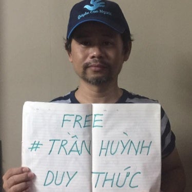 Phan Van Bach carries a sign supporting political prisoner Tran Huynh Duy Thuc.