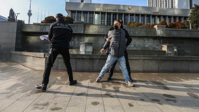 Police Police seize a poster that reads “Journalism is Not a Crime” during a protest by journalists in front of the Azerbaijan parliament building