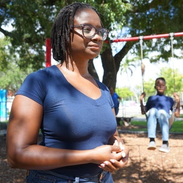 A woman stands in front of a boy on a swingset