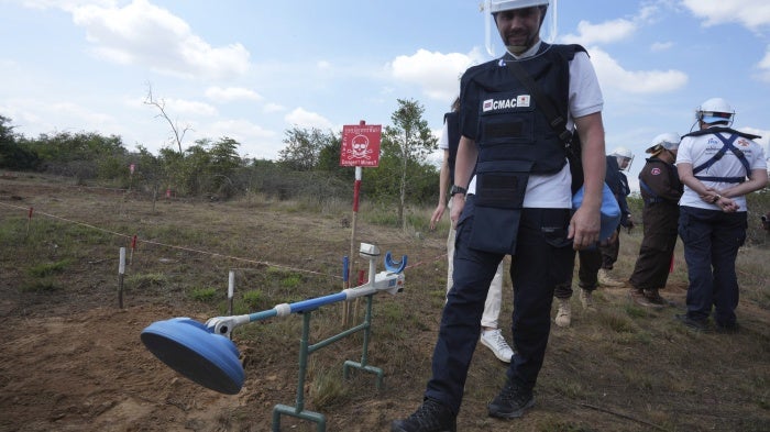 Demining equipment shown next to a deminer in training. 