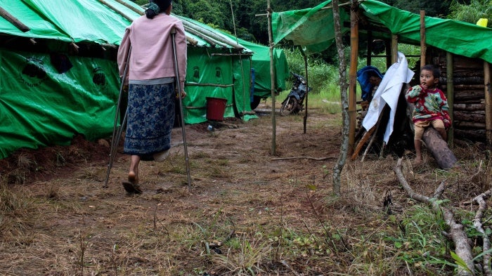 Hla Win walks with crutches near her son at a displacement camp near Pekon township, Myanmar, July 29, 2023. 