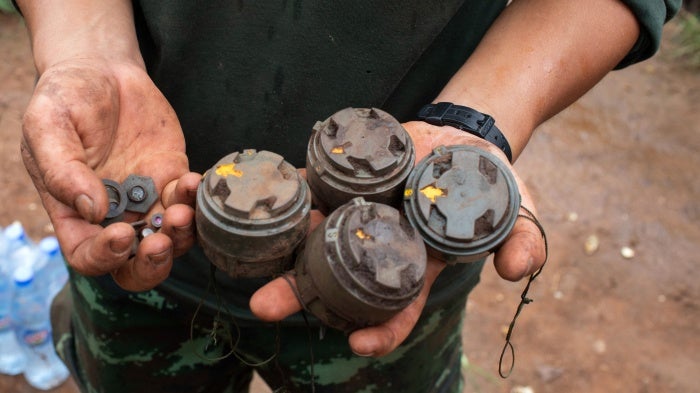 A member of the opposition Karenni Nationalities Defence Force holds antipersonnel mines planted by the Myanmar military and removed during demining operations near Pekon township, July 11, 2023.