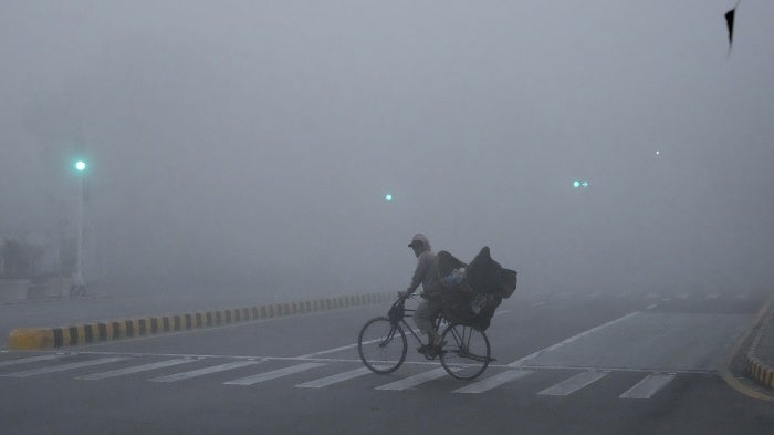 A cyclist crossing a road amid intense smog