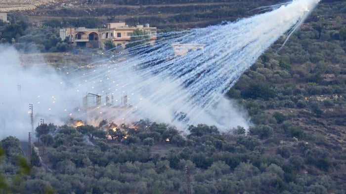 Artillery projectile containing white phosphorus bursts over a village