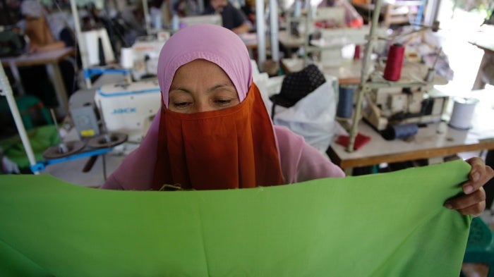 A worker sews a garment at a home-based apparel production operation in Bogor, Indonesia, March 4, 2021.