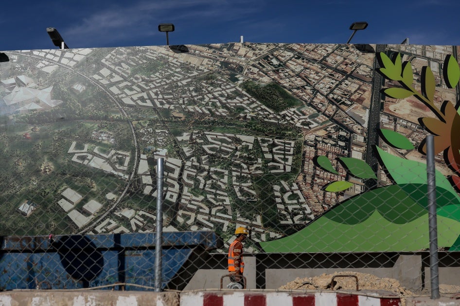 A construction worker passes an advertisement for the King Salman Park gardens and canals development in Riyadh